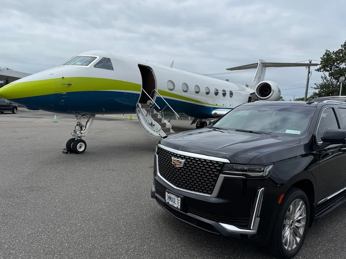 Black Cadillac Escalade parked beside a private aircraft